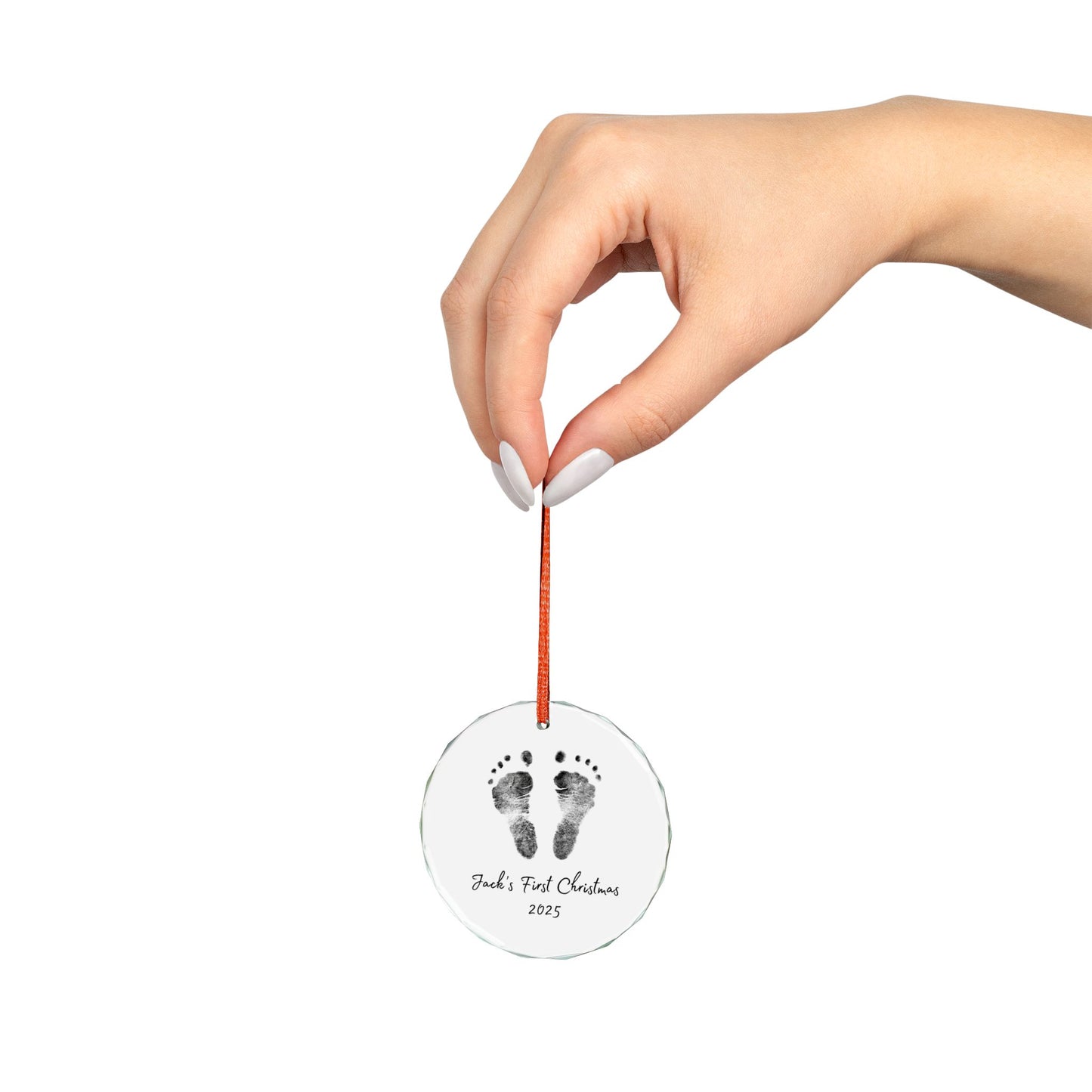Hand holding a round ornament with footprints and text on a white background
