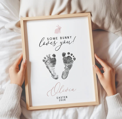 Framed keepsake with baby footprints and text held by hands on a soft surface