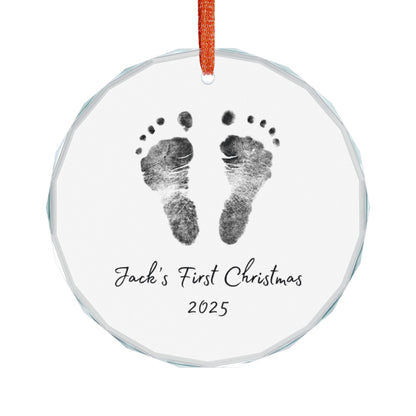 Round glass ornament with personalized baby footprints and 'First Christmas 2025' text on a white background.