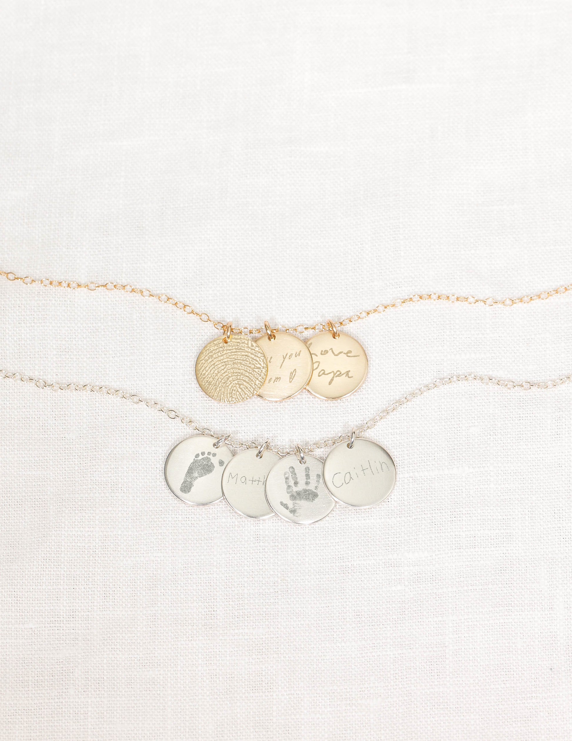 Gold and silver necklaces with engraved charms on a white background