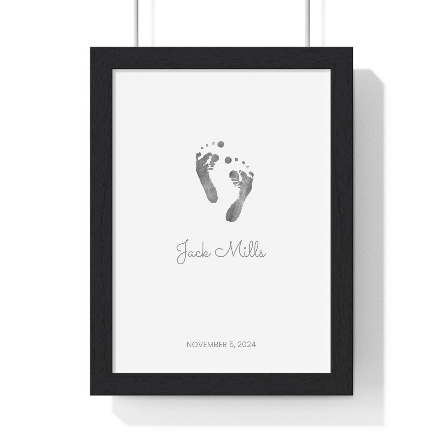 Framed keepsake print with baby footprints on a white background with black frame.